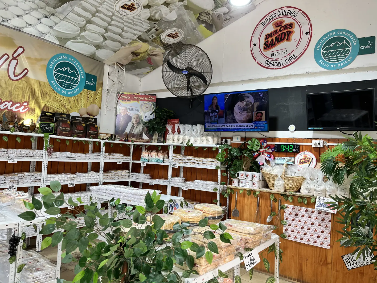 Interior del local de Dulces Sandy en Curacaví: estantes con dulces chilenos, el letrero «Dulces chilenos desde 1995» y el sello de Indicación Geográfica en la pared